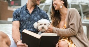 Casal feliz lendo livro junto com um cachorro